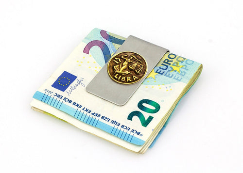 Libra zodiac money clip holding folded euro banknotes.